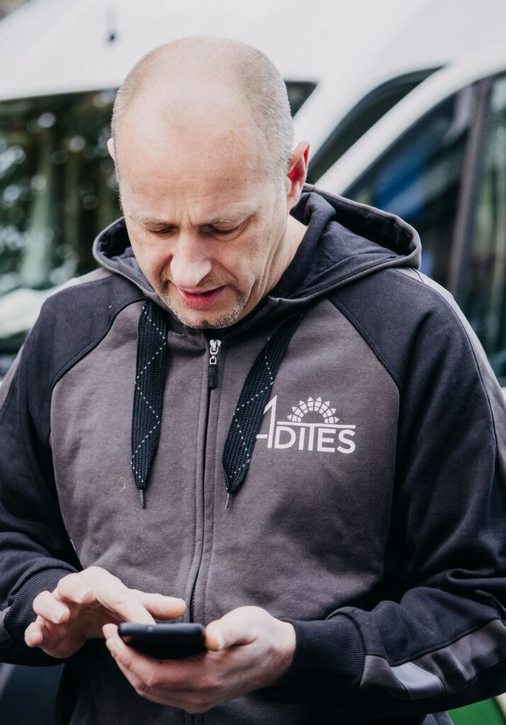 Mann tippt auf Smartphone mit Kapuzenjacke.