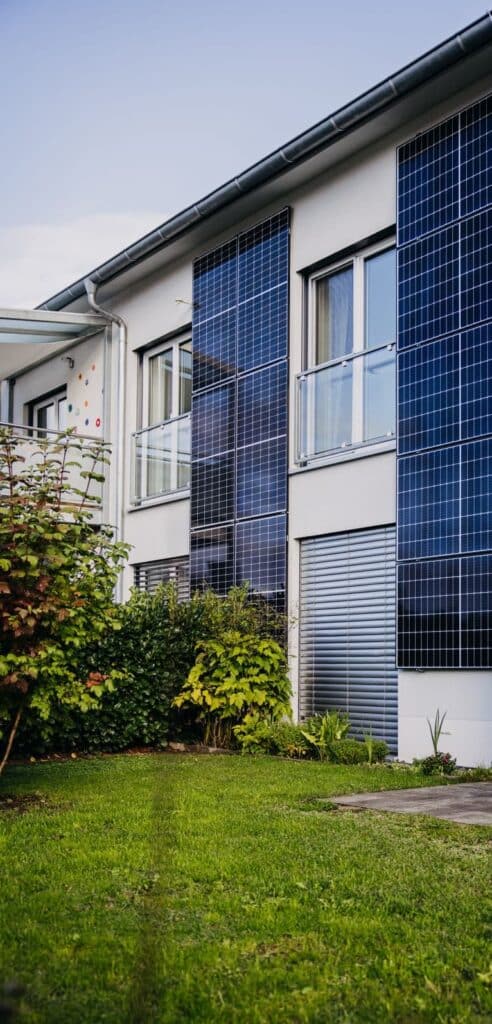 Hausfassade mit Solarzellen und Garten